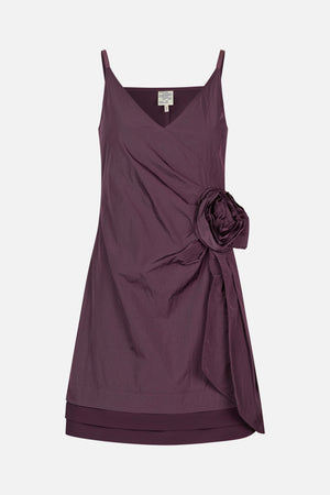 Front view of a plum sleeveless dress with thin straps, a V-neckline, and a large fabric flower detail at the side.