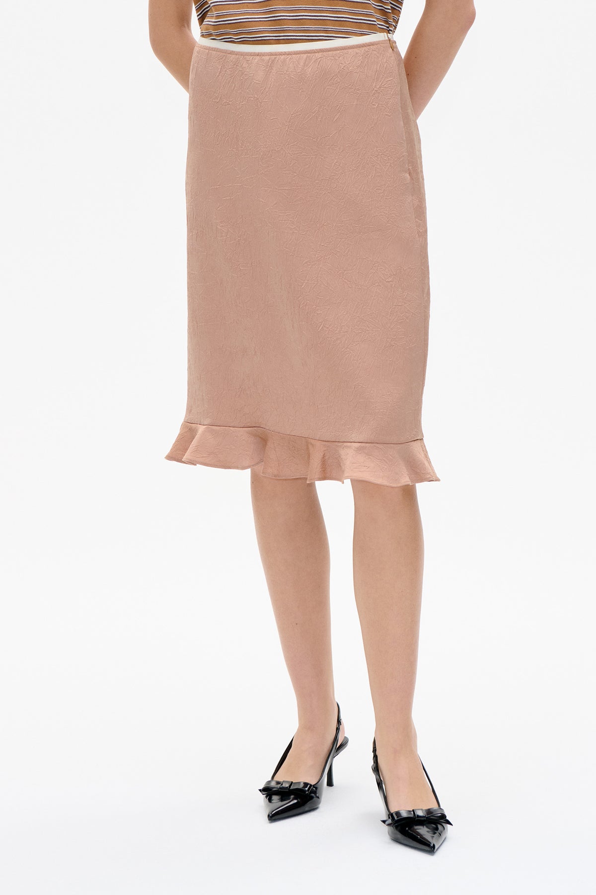 Front view of a dusty rose skirt with a crinkled texture and flounced hem, styled with a brown striped top.