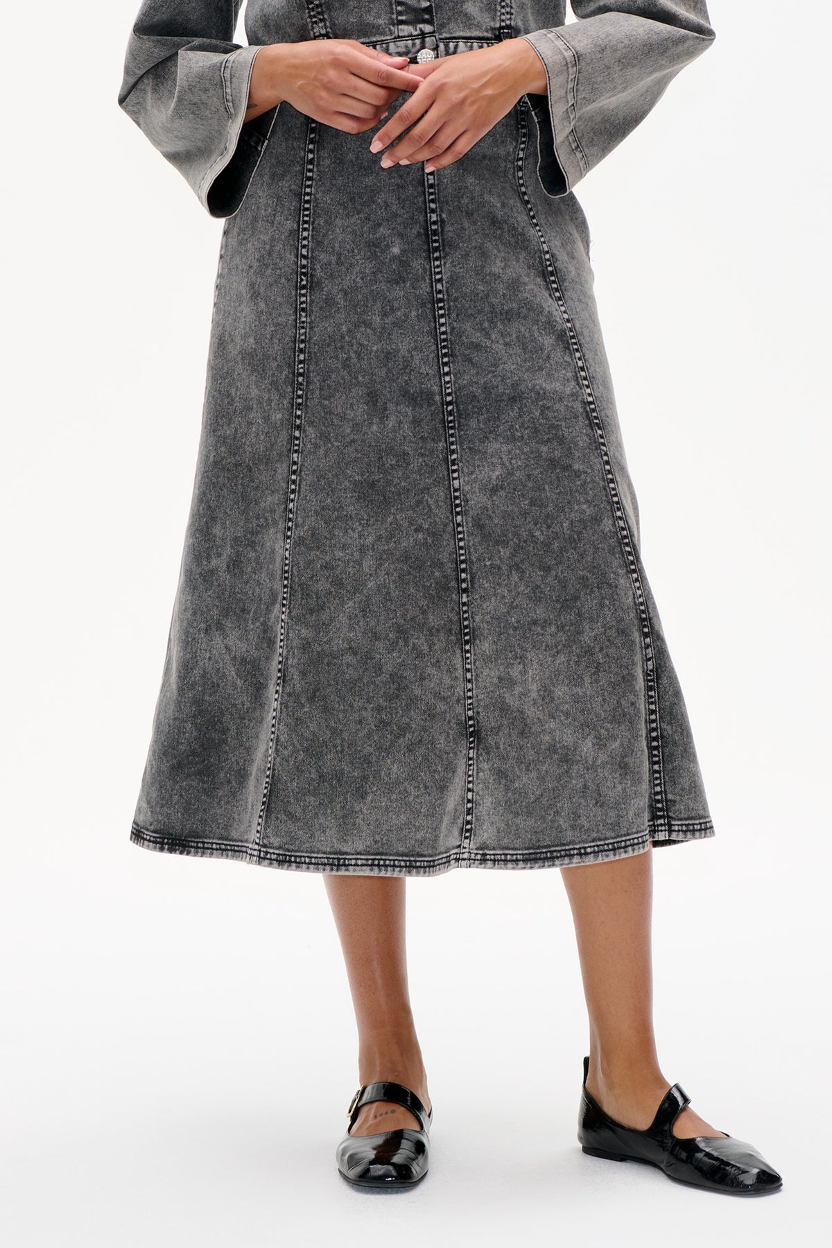 Front detail of a grey acid-wash denim dress with oversized sleeves and prominent contrast stitching