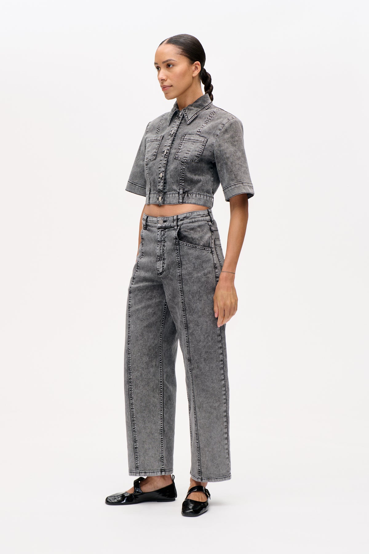 Model wearing a grey acid-wash denim jacket with short sleeves and chest pockets, paired with matching wide-leg jeans.