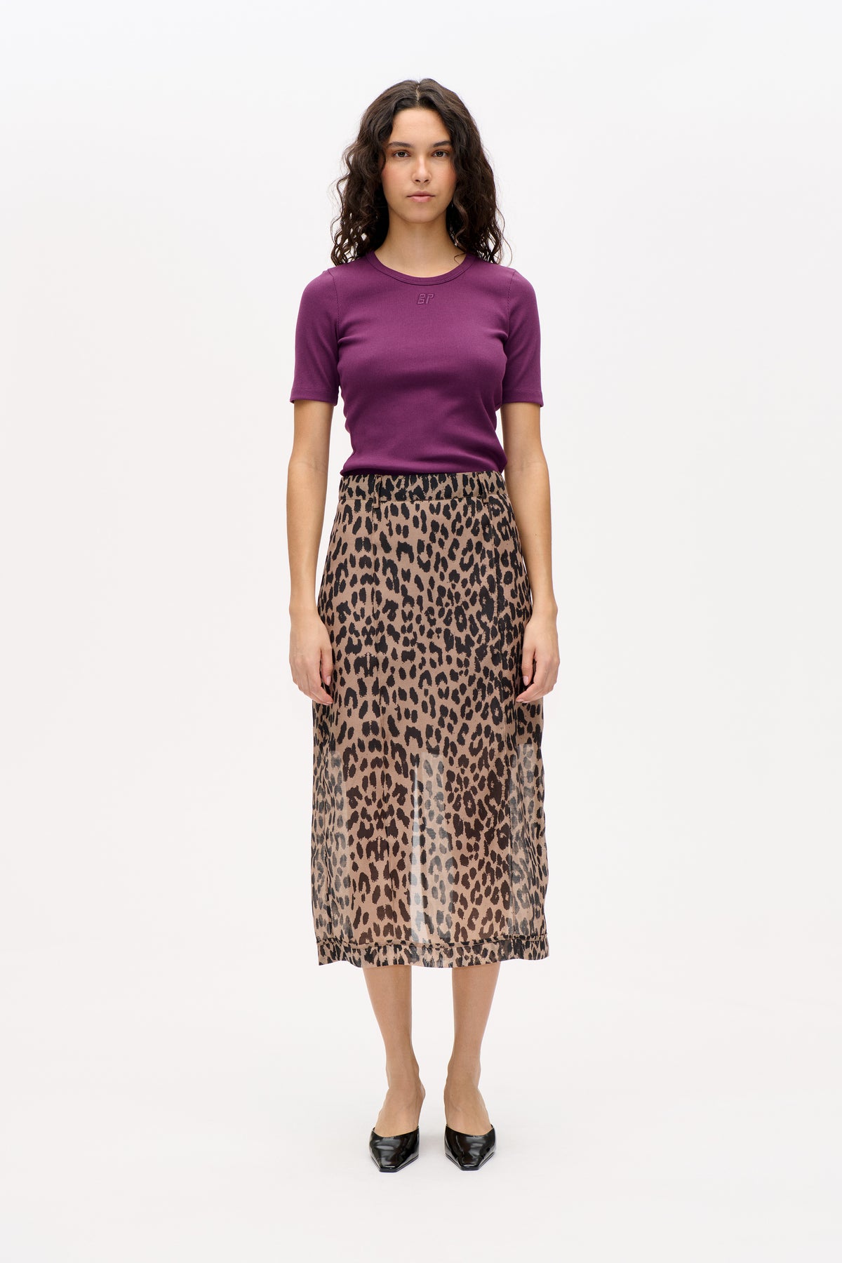 Front view of a model wearing a plum short-sleeved T-shirt with a small embroidered chest logo and a beige leopard-print midi skirt.