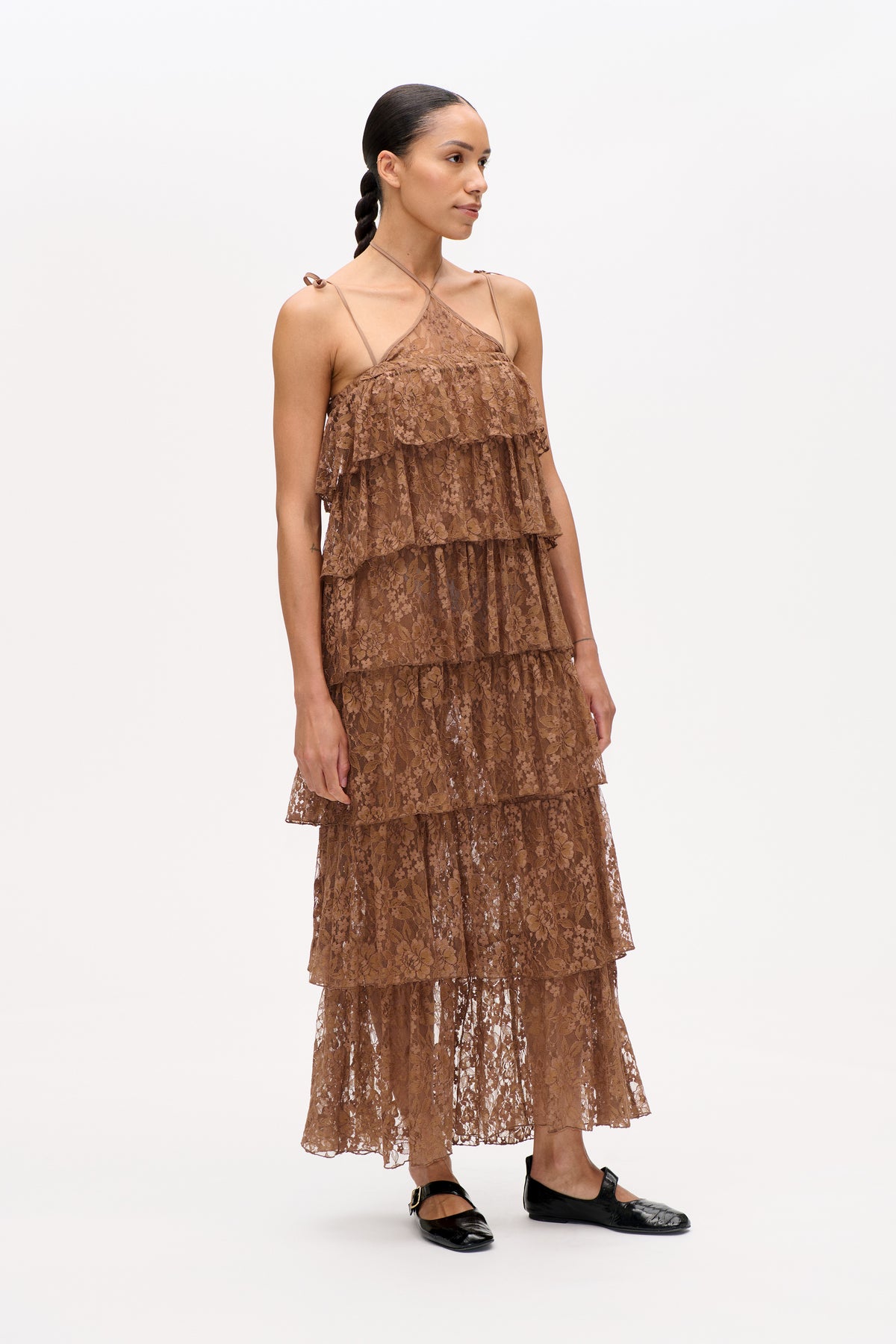 Model wearing a tiered brown floral lace dress with a halter neckline and thin shoulder ties, shown from the front.