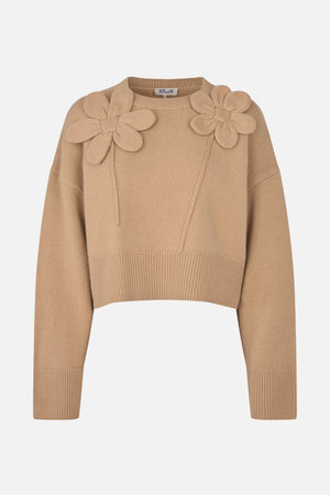 Front view of a beige knitted sweater with long sleeves, ribbed edges and two large raised flower appliqués on the shoulders.