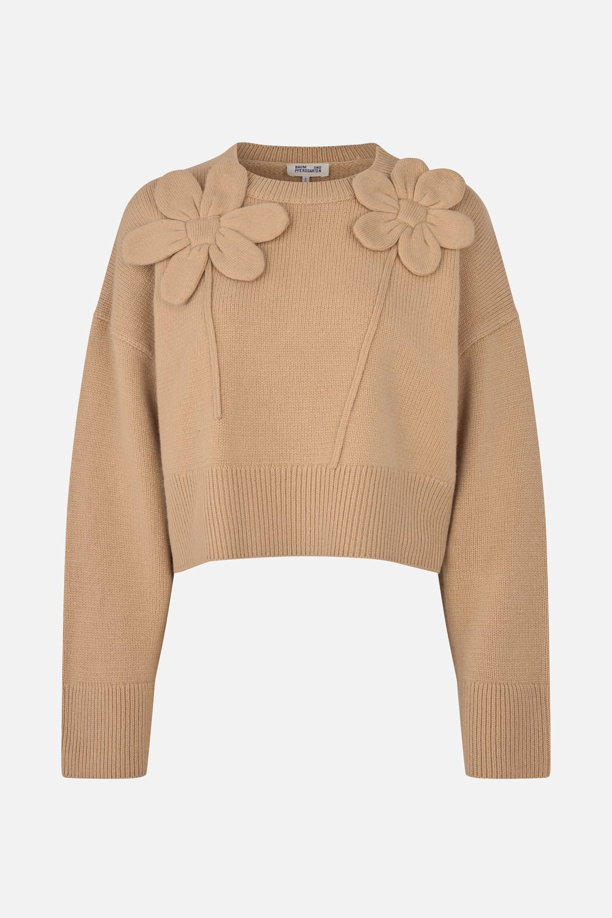 Front view of a beige knitted sweater with long sleeves, ribbed edges and two large raised flower appliqués on the shoulders.