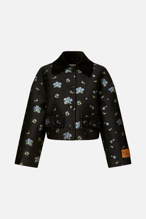 Front view of a black cropped jacket with blue and green floral motifs, a wide corduroy collar, covered buttons and flap pockets.