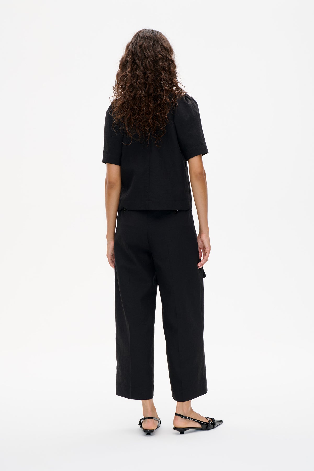 Vue de dos d'un mannequin portant un haut noir à manches courtes et un pantalon large court assorti.