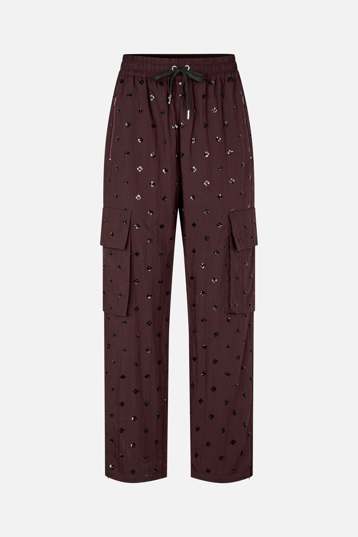 Front view of deep burgundy wide-leg trousers with scattered black and silver flower motifs, an elastic drawstring waist, zip pockets and cargo flap pockets.