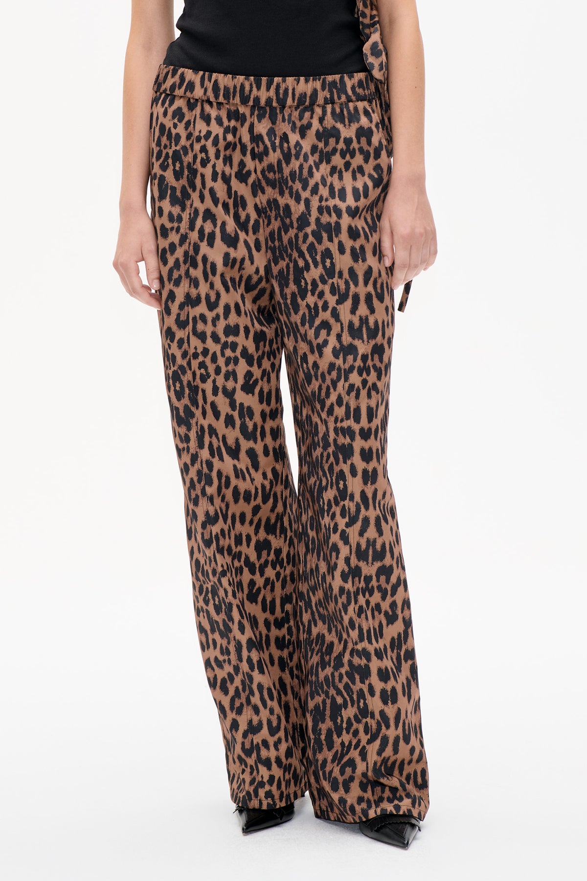 Detail der Vorderseite einer braun-schwarzen Hose mit Leopardenprint, gerafftem Bund und weitem Bein, gestylt mit schwarzem Top.