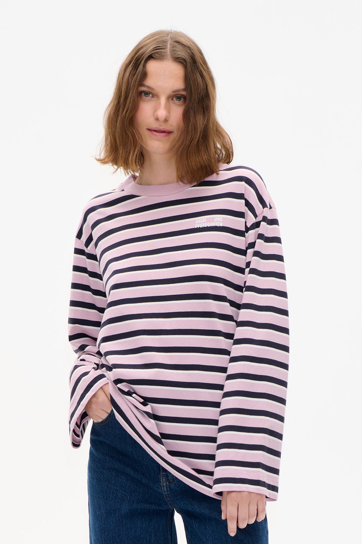 Front detail of a long-sleeved top with pink, navy and cream horizontal stripes and a small white chest logo.