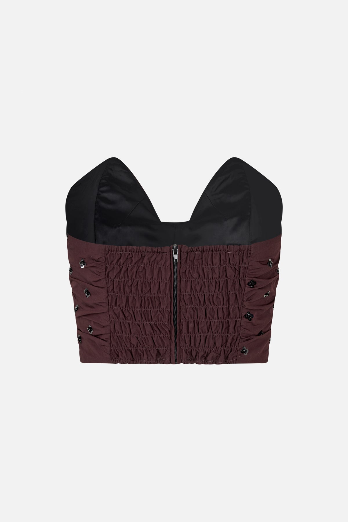 Front detail of a burgundy ruched top with black structured bust panels, a central zipper and scattered embellishments.