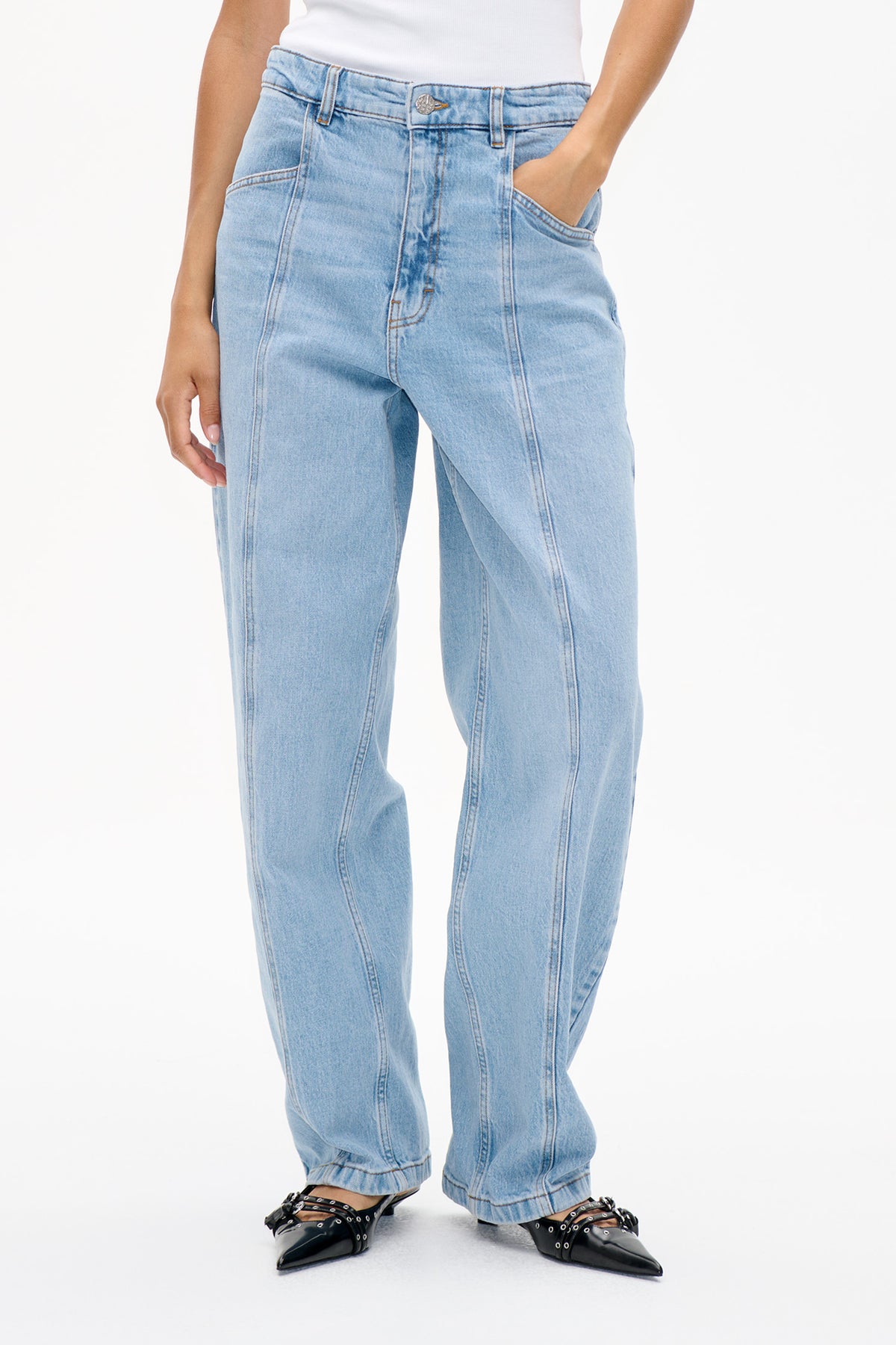 Front detail of light blue washed jeans with a button waistband, belt loops, curved seams and wide legs.