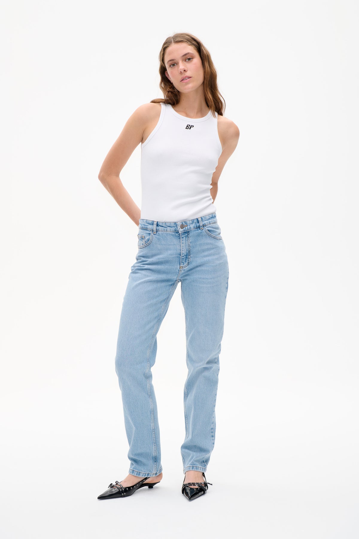 Model wearing a white ribbed sleeveless top with a small black BP logo, light-wash jeans and black pointed flats against a white background.
