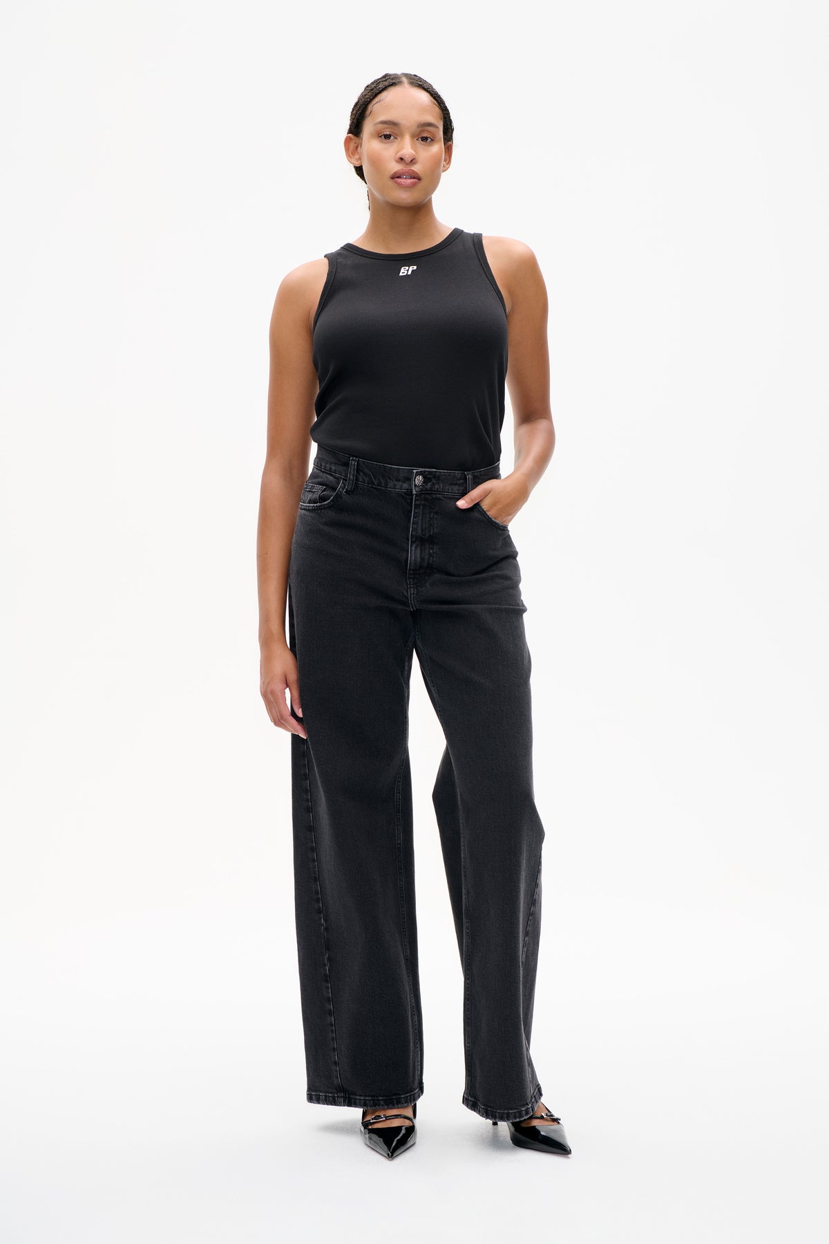 Front view of a model wearing a black ribbed sleeveless top with a small white BP logo and dark wide-leg jeans.