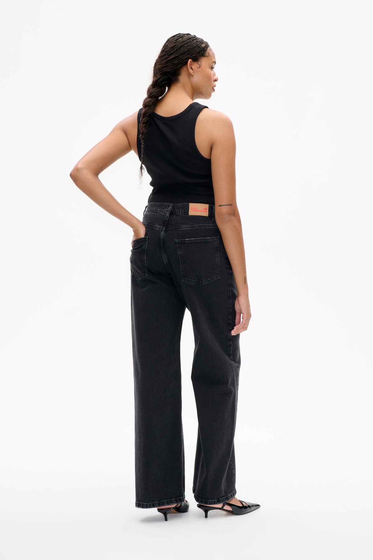 Back view of a model wearing a black sleeveless tank top and charcoal wide-leg jeans with back pockets.