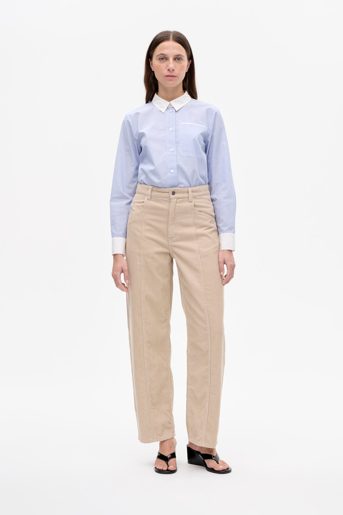 Front view of a pale blue shirt with fine white stripes, a white collar and cuffs, and a trimmed chest pocket, worn with beige trousers.