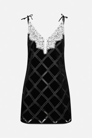 Front view of a black sleeveless slip dress with a diamond lattice pattern, white lace V-neck and bow-tied shoulder straps.