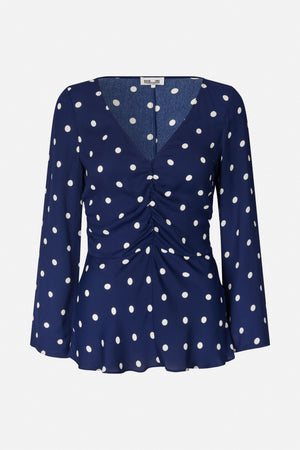 Navy long-sleeved blouse with white polka dots, a V-neckline, gathered front and flared hem