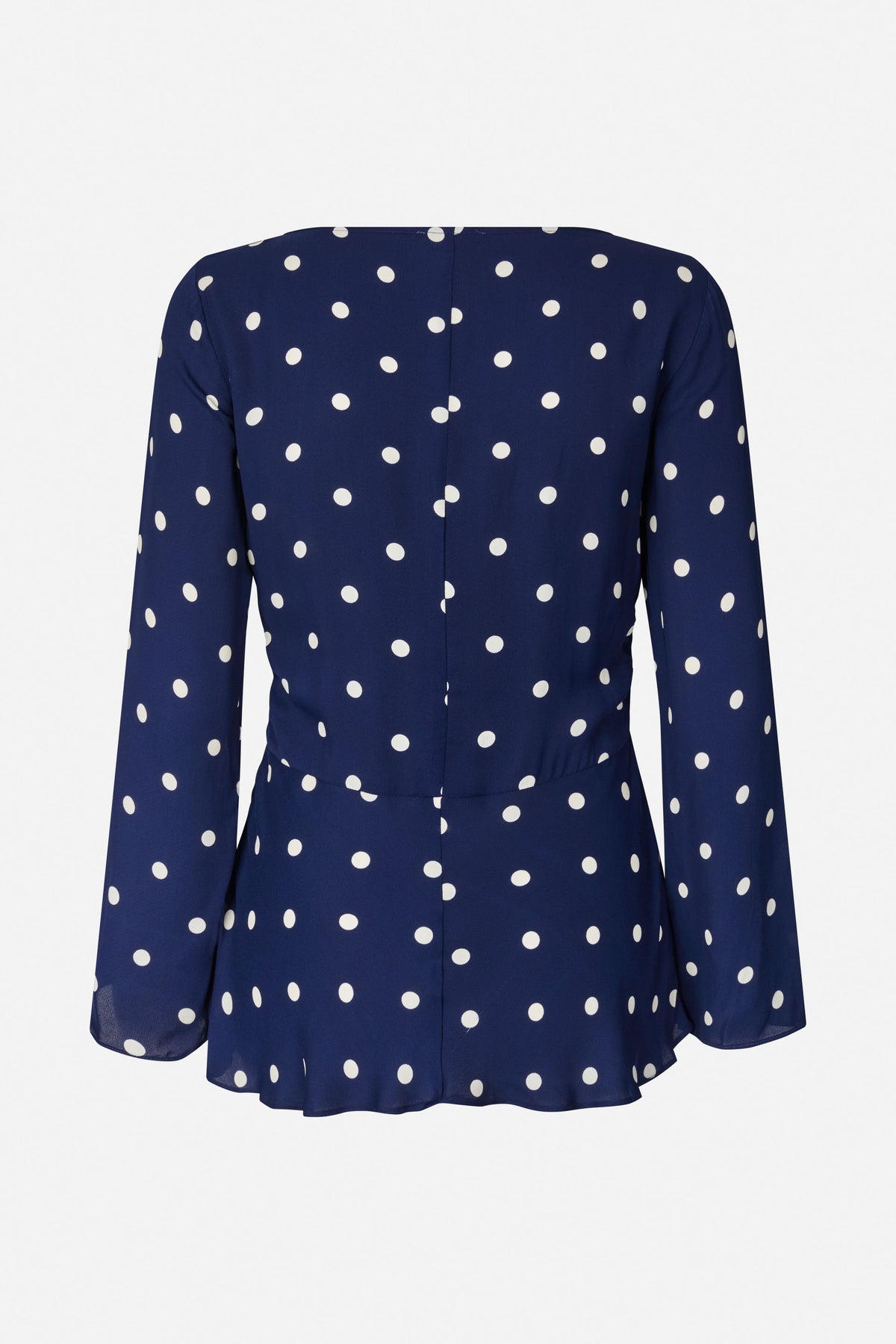 Back view of a navy long-sleeved blouse with white polka dots, a centre seam and a flared peplum hem.