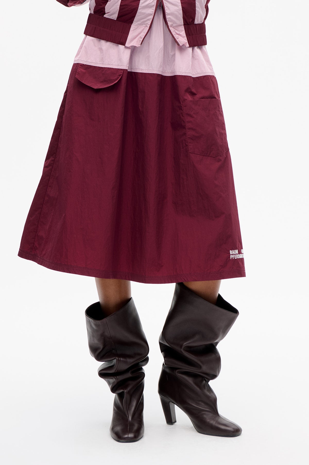Close-up of a burgundy and pale pink colour-block dress with a front zip, elastic waist and large skirt pockets.