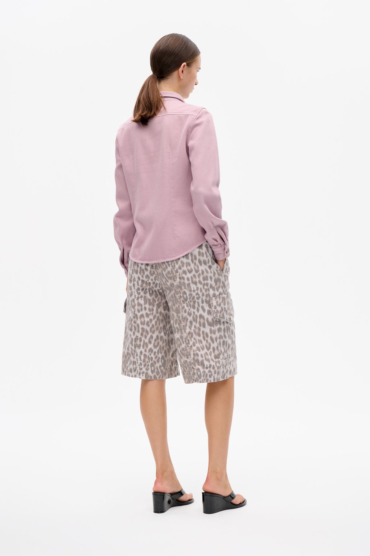 Back view of a model wearing a pale pink collared jacket and beige shorts with a grey-brown animal print.