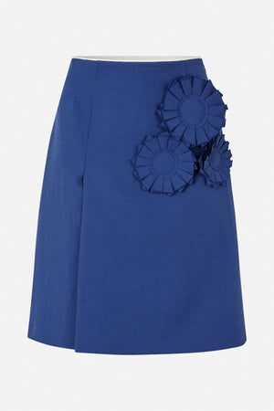 Blue A-line skirt with layered rosette appliqués clustered at the front waist and hip, shown from the front.