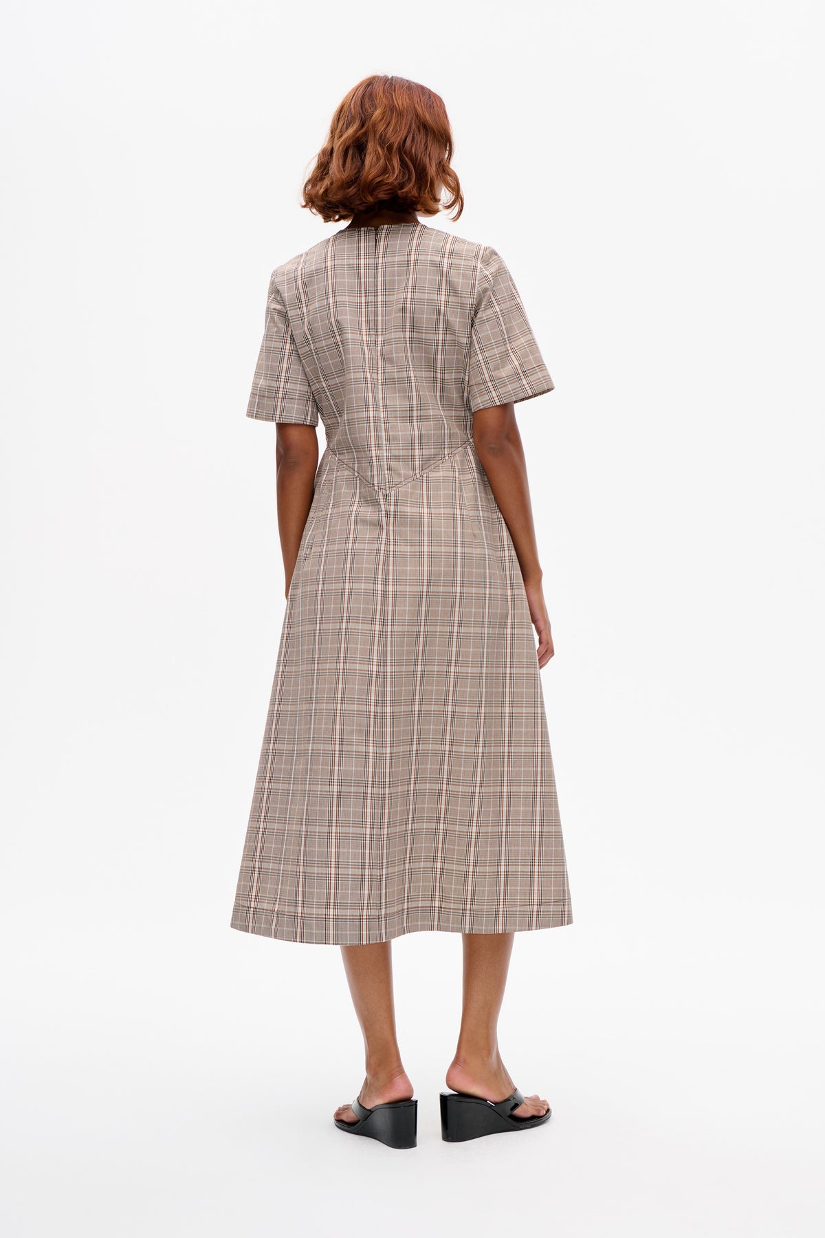 Back view of a short-sleeved beige plaid dress with a shaped waist and knee-length flared skirt
