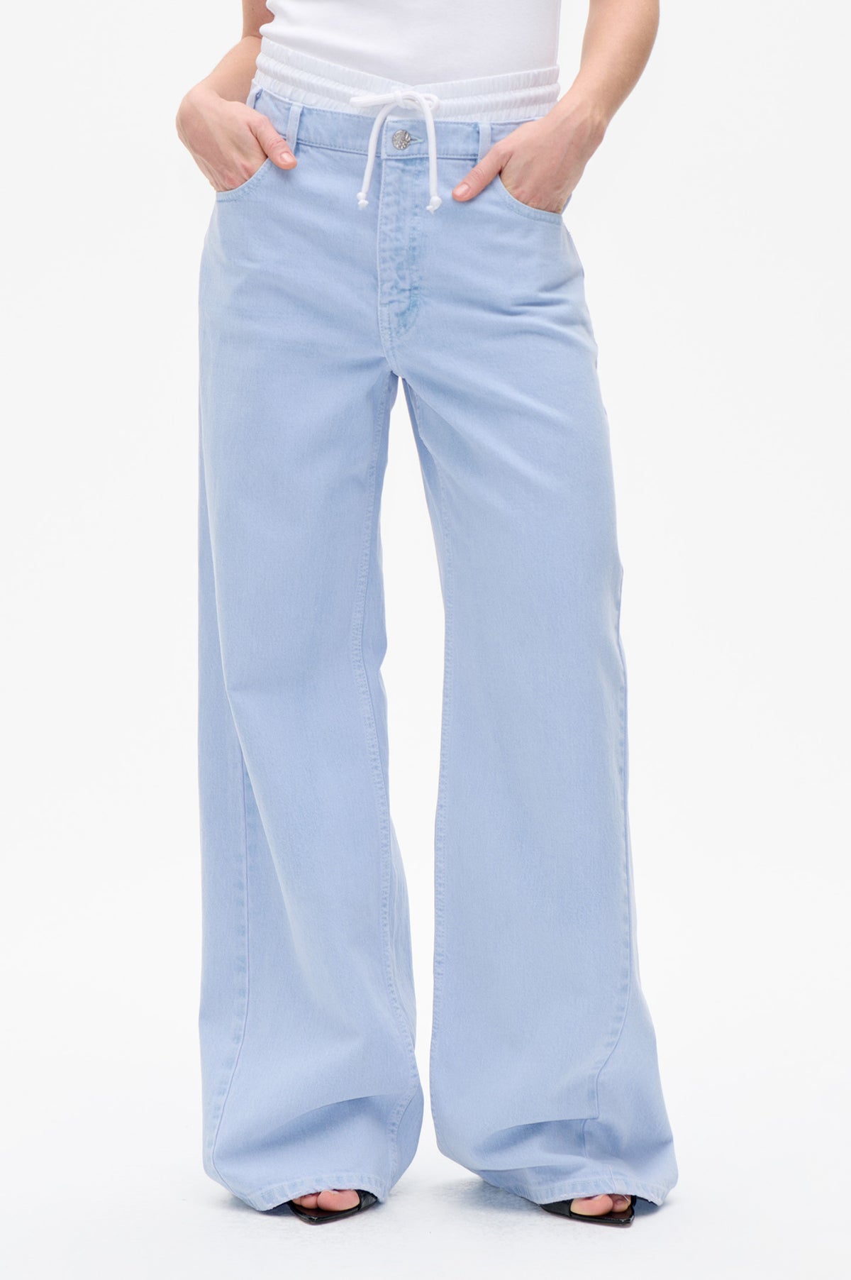 Front detail of light blue wide-leg jeans with an elastic drawstring waistband, button closure and front pockets.