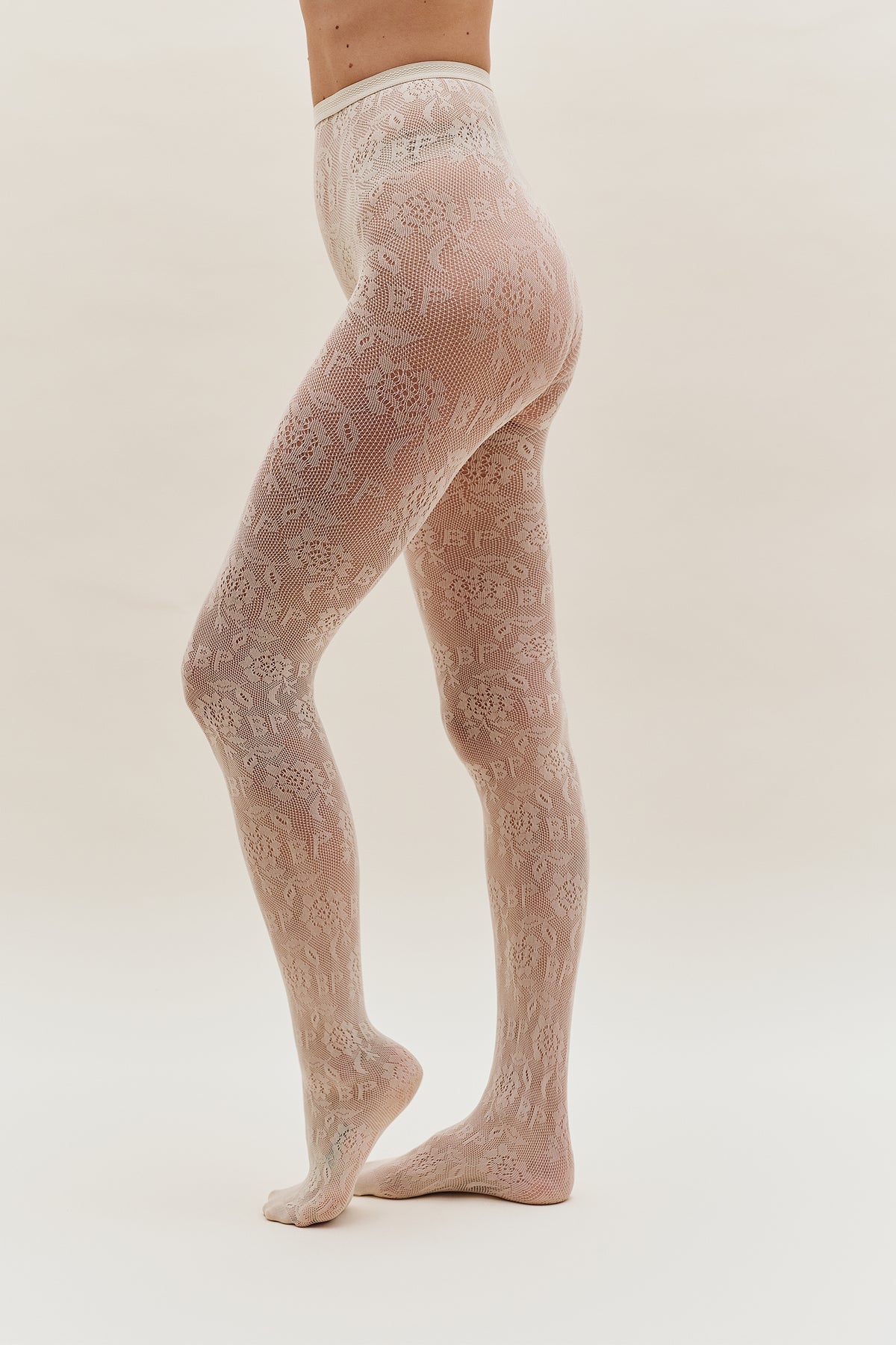 Model wearing sheer ivory tights with an all-over floral lace pattern, shown from waist to feet.